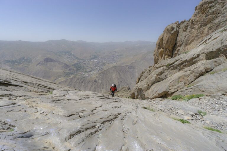 A hiker descends a rocky mountain path in Hakkari, Türkiye, showcasing adventure and natural beauty.