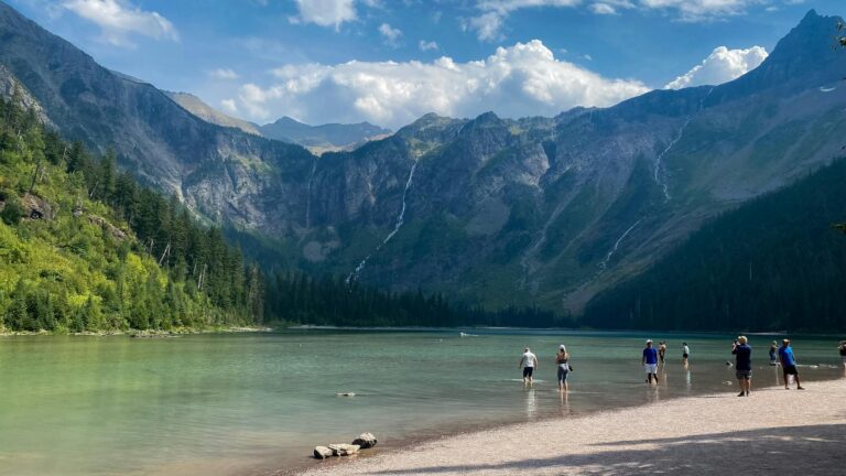 Experience a tranquil scene by a mountain lake with people enjoying the serene environment.